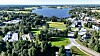 Ilmasta kuvattu vihreä asuinalue, tie ja suuri järvi.