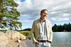 Frank Hoverfelt seisoo kallioisella rannalla Vitsandissa metsän ja tyynen vesistön äärellä.